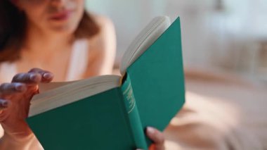 Tasasız öğrenci kitap okuyor hafta sonları rahat bir yatakta uzanıyor. Gülümseyen esmer, rahat yatak odasında rahatlatıcı romanlara dalmış. Ev işlerinde edebiyat hobisi yapan mutlu bir kadın..