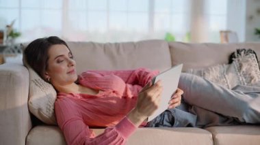 Sakin bir kadın kitap okuyor. Ev yapımı bir sabahta rahat bir kanepede uzanıyor. Evde kanepede dinlenen esmer kadın tableti izliyor. Modern iç mekandaki sekme bilgisayarında gülümseyen bayan gezinti e- postası.