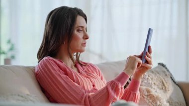 Bayan internet bankacılığı uygulaması cep telefonu ev koltuğu kapanışında finansal geliri sevindiriyor. Akıllı telefon koltuğunda harika haberler okuyan aşırı neşeli bir kadın. İçerideki telefon mesajıyla heyecanlanan esmer kadın şaşırdı.