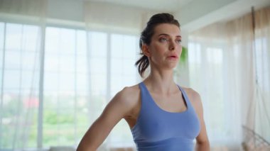 Spor kıyafetli kadın, sabah oturma odasında derin bir nefes alıp veriyor. Evde antrenmandan sonra dinlenen güzel bir kadın. Sakin esmer, farkındalık egzersizi yapıyor. Dairede huzurlu bir anın tadını çıkar.