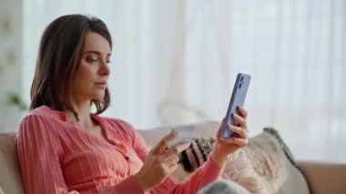 İnternetten cep telefonu alışverişi yapan bir bayan daire koltuğunu kapatıyor. Sakin bir kadın kredi kartı bilgilerini giriyor ve evdeki kanepeye internet alımı yapıyor. Gülümseyen esmer, mal sipariş ediyor, ödemeyi telefonla yapıyor..