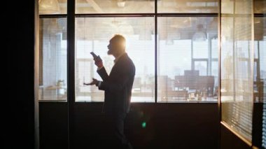 Müdür cep telefonu hoparlöründen konuşuyor. Gün batımını kapatıyorum. Siluet kıdemli işadamı koridordaki akıllı telefon sesli mesajını kaydediyor. Olgun yönetici cep telefonuyla dikte ediyor.