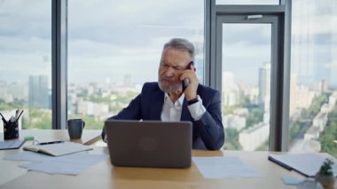 Sorunlu CEO 'nun cep telefonuna bağırması dizüstü bilgisayarın mali raporunu yakından incelemesi. Kızgın, olgun iş adamı ofiste akıllı telefonları tartışıyor. İş yerinde telefon kapama bilgisayarında bağıran çılgın yönetici.