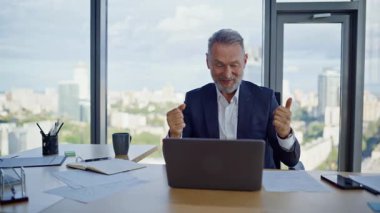 Hevesli bir yönetici bilgisayar kamerasıyla modern ofis kapanışında yaratıcı fikirleri tartışıyor. Gülümseyen yaşlı iş adamı videosu arıyor. Mutlu lider iş yerindeki bilgisayarın sanal konferansından zevk alıyor