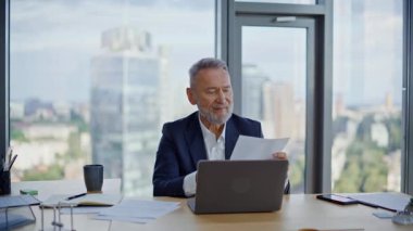 Başarılı bir girişimci ofis kapanışında karlı anlaşmanın tadını çıkarıyor. Kıdemli işadamı, başarı hissederek belgeleri inceliyor. Gülümseyen sakallı patron şirketin mali sonuçlarını analiz ediyor.