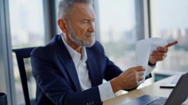 Üst düzey finansör elleri dizüstü bilgisayara yakın çekim yapıyor. Gri saçlı işadamı, bürodaki verileri tatminsiz bir şekilde kontrol ediyor. Stresli yönetici raporları okuyor. Çökmekte olan belgeleri atıyor. Endişeli kriz..