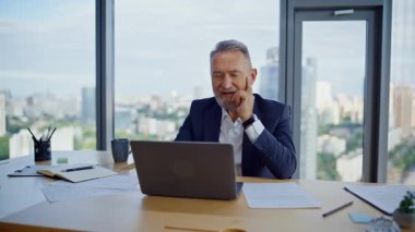 Modern iş yerinde gülümseyen profesyonel e-posta. Mutlu kıdemli iş adamı ofiste bilgisayar görüntüsü veren mali rapordan memnun. İşletme projesinde çalışan başarılı CEO notları alıyor.