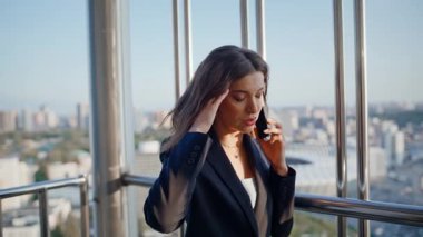 Endişeli yönetici, balkon ofis binasında telefonla konuşuyor. Stresli iş kadını cep telefonunun terasında problemden şikayetçi. Endişeli kadın çalışan telefonla iş konularını tartışıyor