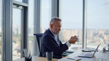 Yaşlı yöneticiler ofise iş kağıtlarını atarken video aramasında hayal kırıklığına uğradılar. Öfkeli iş adamı duygusal olarak stresli bir şekilde bilgisayarı kapatıyor. Öfkeli patron iş yerinde stresli online toplantısını bitirdi