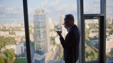 Yönetici, panoramik pencere iş merkezinin yanında cep telefonundan sesli mesaj bırakıyor. Üst düzey işadamı hoparlörden konuşuyor. Akıllı telefondan notaları dikte eden zarif bir çalışan..