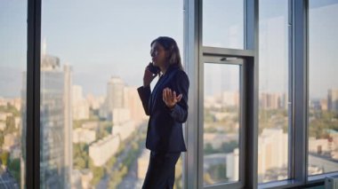 Şirket yöneticisi ofis panoramik penceresinin yanında cep telefonu pazarlığı yapıyor. Şık bir iş kadını cep telefonundan şehir manzarasına bakıyor. Kendine güvenen kadın CEO koridorda akıllı telefonla iş tartışıyor..