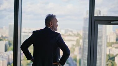 Başarılı lider panoramik pencerenin yanında güzel bir şehre yakın duruyor. Üst düzey işadamı ofis binasının manzarasının keyfini çıkarıyor. Kurumsal işleri yarıda bırakan zarif bir girişimci.