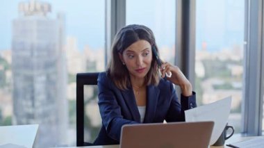 Şirket yöneticisi cep telefonuyla görüşüyor. Modern ofiste dizüstü bilgisayara bakıyor. Başarılı bir iş kadını iş yerinde akıllı telefonu arıyor. Zarif kadın yönetici proje detaylarını telefonla açıklıyor.