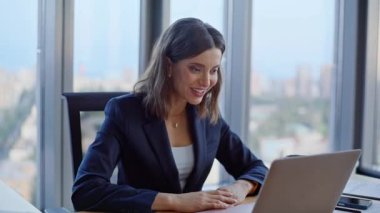 Modern ofiste online toplantıdan başlayarak dizüstü bilgisayarlı web kamerasıyla gülümseyen bir yönetici selamlıyor. Hevesli iş kadını iş yerinden el sallıyor. Mutlu bayan sanal konferansın tadını çıkarın..