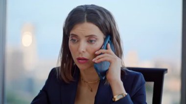 Ofis panoramik penceresinin yanında oturan akıllı telefondan endişelenen CEO. Zarif bir iş kadınının cep telefonuyla iş görüşmesi. Ciddi kadın patron hoşnutsuz cep telefonu sohbeti.