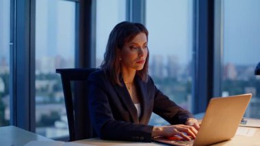 Modern iş yerlerinde dizüstü bilgisayar yazan fazla mesai çalışanları. Üzgün iş kadını gece geç saatlere kadar bilgisayarda çalışıyor. Sadece lamba ışığında iş meselelerini çözen motivasyonsuz kadın yönetici..