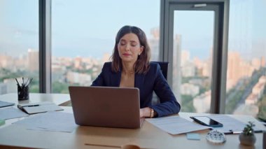 Ofis çalışanı dizüstü bilgisayarda modern çalışma alanlarını tarıyor. Motivasyonsuz kadın yönetici, bilgisayar kapağını kapatıyor ve ağır iş görevleri altında eziliyor. İş yerinde proje üzerinde düşünmekten yorulmuş zarif bir iş kadını..