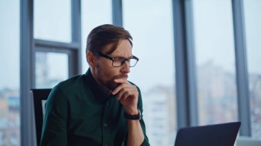 Modern ofiste çalışan bir çalışanın bilgisayarında işten çıkarma bildirimi okuması şok edici. Gözlüklü stresli işadamı, bilgisayarın duygusal olarak kapanması konusunda kötü haber verdi. Gergin yönetici umutsuzluk hissediyor.