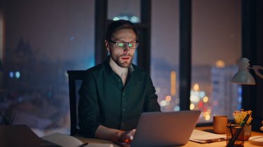 Profesyonel danışman, gece ofisindeki çağrıya cevap veriyor. Kapanış notları yazıyor. Fazla mesai çalışanı cep telefonu sohbetine başla. Çalışma masasında dizüstü bilgisayarla otur. Gözlüklü sakallı iş adamı telefonla konuşuyor..