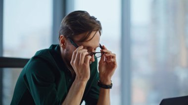 Modern iş yerinde gözlük çıkarmayı düşünen düşünceli bir proje. Sakallı işadamı, ofis çalışma alanında oturarak yeni fikirlere kafa yoruyor. Profesyonel girişimci planlama stratejisi.