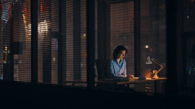 Startuper, gece ofisinde online projeyi analiz ediyor. Dark Company 'nin iş yerinde dizüstü bilgisayarda çalışan çalışkan bir iş kadını. Ciddi kadın profesyonel programlama fazla mesaisi bilgisayar ekranına odaklandı.