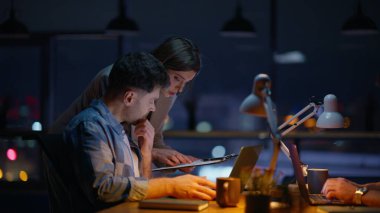 Kadın asistan gece açık mekan kapanış belgeleri gösteren geliştiriciye yardım ediyor. Geç kalmış şirket arkadaşları birlikte proje planlamayı tartışıyorlar. Şirket danışmanı karanlık akşam işyerinde stajyerlerle konuşuyor. 