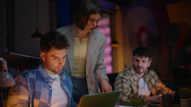 Grup tasarımcıları gece iş yerinin iç kısımlarında beyin fırtınası yapıyorlar. Ofis masasında dizüstü bilgisayar arayan genç meslektaşlar. Ekip lideri kadın, açık alanda son teslim tarihi olan iş arkadaşlarına yardım ediyor