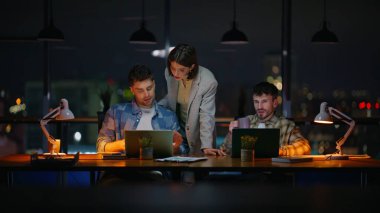 Karanlık panoramik pencere ofisindeki danışman kadın yöneticiler. Birlikte çalışan geç dönem bilgisayarları. Patron astları akşam işyerinde dizüstü bilgisayar arıyorlar. Gece denetçilerinin teslim tarihi var.