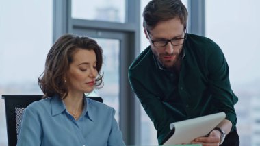 İş adamı, modern ofiste kadın finans müdürüne iş raporu gösteriyor. İki gülümseyen meslektaş el sıkışmayı tartışıyor. Mutlu ortak iş yerinde mali kağıt tatmin