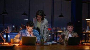 Gece ofisi atmosferde çalışıyor. Akşamları görev çözen üç denetçi. Sanat yönetmeni kadın grafik tasarımcılarının karanlık panoramik konuşmalarına yardım ediyor. İş birliği yaparken takım arkadaşlarıyla konuşuyorlar.