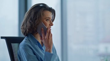 Gülümseyen lider ofisin içinde akıllı telefondan konuşuyor. Mutlu iş kadını portresi cep telefonunda başarıyı tartışıyor. Muhteşem kadın yönetici olumlu cep telefonu sohbetinin tadını çıkarıyor