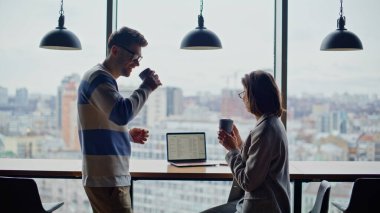 Şehrin arka planında konuşan gülümseyen bir çift. Kasvetli panoramik vitrinlerde içki içen rahat meslektaşlar. Genç ekip işten sonra iletişim kuruyor. İki iş arkadaşı çıkıyor. 