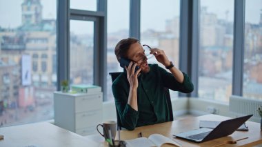 Şirket işyerinde cep telefonundan konuşan zengin bir patron gözlüğünü çıkarıyor. Gülümseyen işadamı modern ofiste dostça telefon konuşmalarının tadını çıkarıyor. Neşeli menajerin hoş bir akıllı telefon iletişimi var..