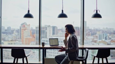 Öfkeli yönetici, ofisteki panoramik pencerede duygusal olarak oturarak telefonu arıyor. Kızgın patronun telefonda bağırması tatminsiz iş sonuçlarını yakınlaştırıyor. Kadın yönetmen sohbeti bitiriyor umutsuzluk hissediyorum 