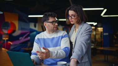 Çağdaş ofiste dizüstü bilgisayarda çalışan sanat yönetmenleri. Kadın asistan konuşuyor. Modern Buro 'daki kontrol projesi. Bilgisayar ekranını inceleyen yeni fikirleri tartışan iki meslektaşım var. 