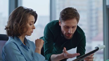 İş adamı ofis ışıklarının iç tarafındaki kadın çalışana belgeleri açıklıyor. Sakallı iş adamı iş kadınına iş verilerini gösteriyor. İş yerinde mali raporu tartışan iki meslektaş