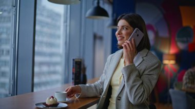 Dinlenmiş esmer konuşan cep telefonu bekleme toplantısı modern kafe kapanışında. Akıllı telefondan konuşan çekici genç bir kadın küçük restoran tezgahında oturuyor. Çevrimiçi danışman akıllı telefon sohbeti