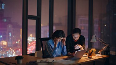 Yorgun takım, ofis panoramik penceresinde dizüstü bilgisayarı arıyor. Stresli bir kadın şakaklara masaj yapıyor endişeli bir işadamıyla konuşuyor. Mesai saatlerini birlikte geçiren iki iş arkadaşı..