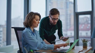 Modern ofisteki iş raporlarında işbirliği yapan dost canlısı iş arkadaşları. Profesyonel işadamı elinde laptop ekranına işaret eden bir iş kadını tutuyor. Birlikte çalışan kendine güvenen meslektaşlar..