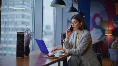 Kafeteryadaki bilgisayar ekranında akıllı telefondan konuşan ciddi bir avukat. Kendine güvenen bir kadın cep telefonuyla kafeterya masasında uzaktan kumandayı tartışıyor. Güzel yönetici iş telefonu sohbeti 
