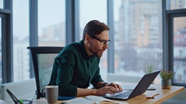 Çok mutlu bir girişimci şirket ofisindeki dizüstü bilgisayarı yakından inceleyerek başarılı oluyor. Duygusal iş adamı iş başarısını heyecanla kutluyor. Mutlu CEO 'lar iş yerinde online galibiyeti kutluyor..