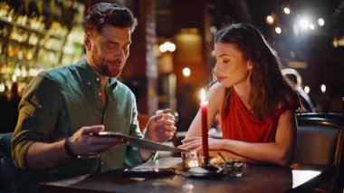 Karanlık Kafe 'nin iç kısımlarında menüye bakan iki arkadaş. Modern gece barında sırayı tartışan gülümseyen bir çift. Mutlu kadın konuşuyor. Akşam restoranında romantik bir buluşmanın tadını çıkarıyor.