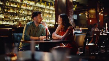 Barda hafta sonunu birlikte geçiren gülümseyen bir çift. Karanlık modern barda romantik bir buluşmada konuşan mutlu genç çift. Neşeli sevgililer loş bir kulüp atmosferinde parlayan mumlarla otururlar..