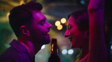 Gece kulübünde dans eden romantik aşıklar birbirlerine yakından bakıyorlar. Gülümseyen kadın, neon ışıkları altında bedenleri şehvetle hareket ettiriyor. Mutlu genç çift gece takılırken enerjik müziğin tadını çıkarıyor..