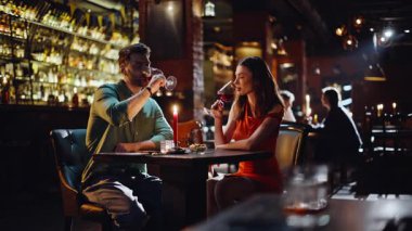 Gülümseyen aşıklar modern barda şarap kadehlerini tokuşturuyorlar. Sevgi dolu koca, lüks bir restoranda evlilik yıldönümü kutlaması yapıyor. Mutlu çift görüşmenin tadını çıkarıyor..