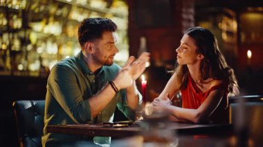 Akşam barında flört eden sevimli bir çift. Gülümseyen kadın barın içinde yanan mumlarla konuşuyor. Mutlu aşıklar geceyi restoranda geçirirler. Romantik duyguların tadını çıkarırlar..