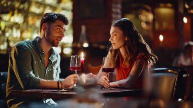 Lüks restoranda kutlama yıldönümünü kutlamak için kadeh kaldıran güzel bir çift. Gülen, sevgi dolu bir çift romantik bir akşam yemeği yiyor ve kırmızı şarap içiyor. Gülümseyen kadın konuşuyor birlikte rahatlıyor..