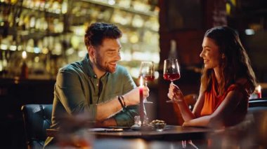 Romantik sevgililer lüks restoranın iç kısımlarında kadeh tokuşturur. Kız arkadaşıyla akşam yemeğinde kırmızı şarap içen gülümseyen erkek arkadaş. Mutlu çift, bardaki lezzetli alkol toplantısının tadını çıkarıyor.