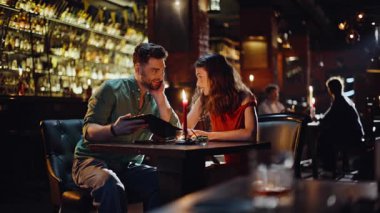 Romantik çift menüyü tartışıyor. Parlayan mumlarla barın içinde rahat bir şekilde oturuyorlar. Gülümseyen adam, güzel bir kadına bağlanma toplantısında düzen teklif ediyor. Mutlu koca eşi modern barda bir akşam geçiriyor..