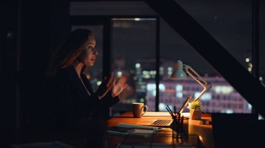 Akşam çalışanı, internetteki röportajı konuşuyor. Karanlık bir evde dizüstü bilgisayarla oturuyor. Pozitif kadın gece sanal buluşmada fikirleri açıklıyor. Yaratıcı iş kadını video arama bilgisayarı iş tartışması